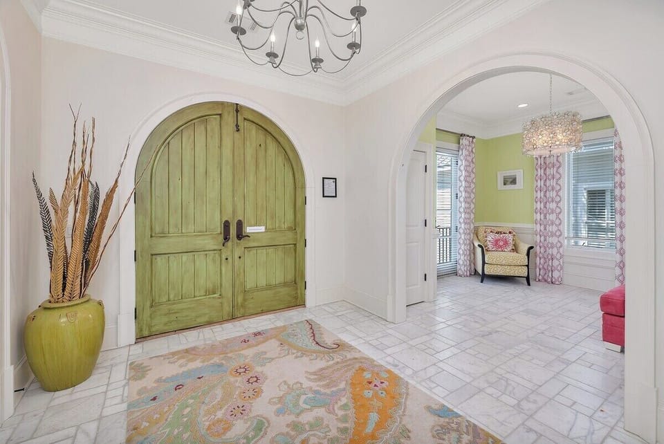 Grand foyer with arched green doors and chandelier
