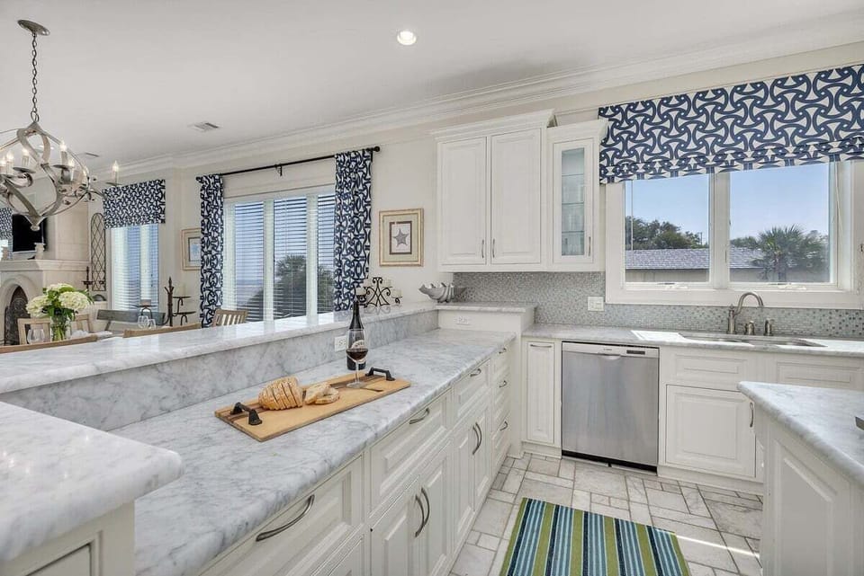 White kitchen with marble counters and blue patterned valances