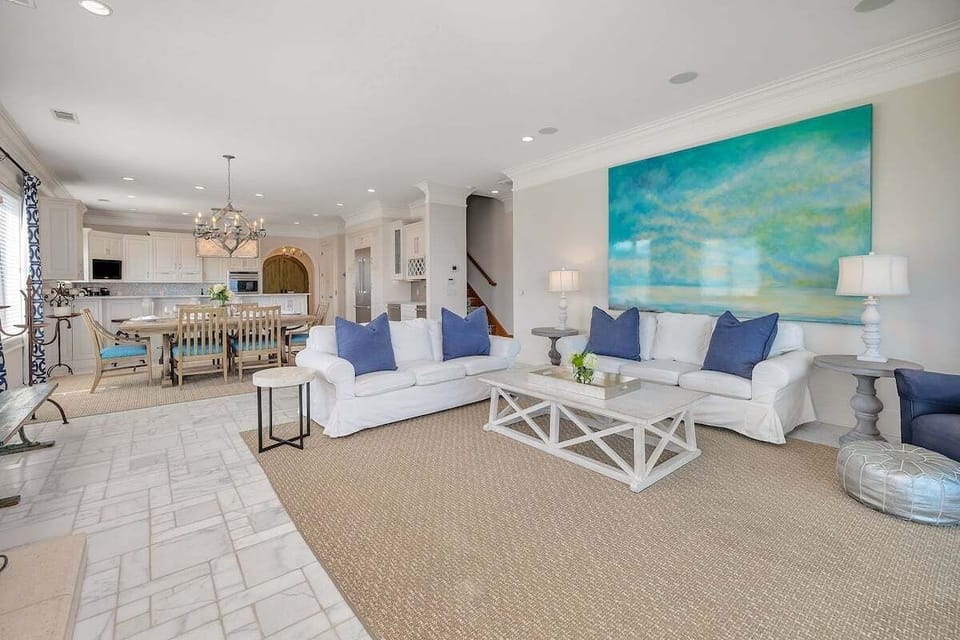 Open living room with white sofas and teal wall art