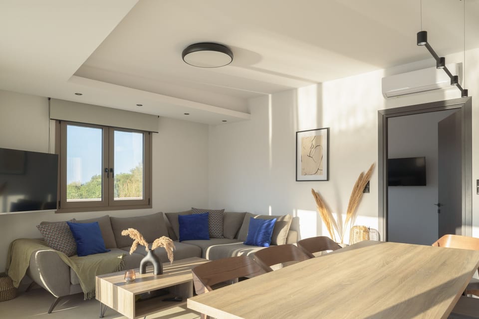 The living room is furnished with a plush corner sofa, a smart TV, and a stylish coffee table.