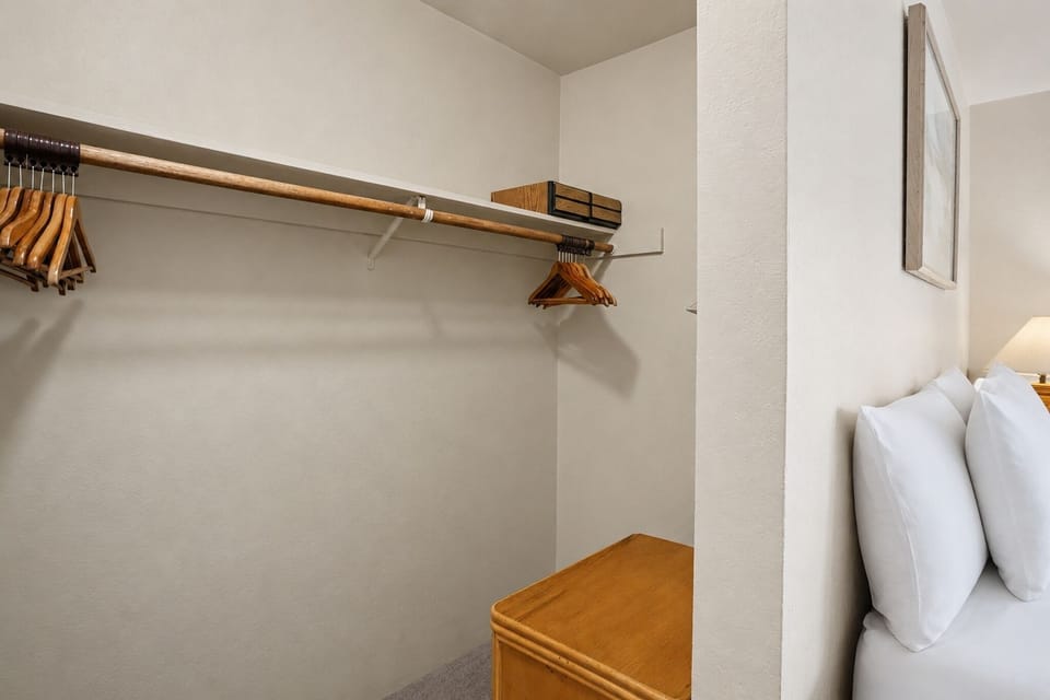 Organize your wardrobe with ease in this walk-in closet featuring plentiful hanging space and upper storage—everything neatly arranged for your vacation essentials.