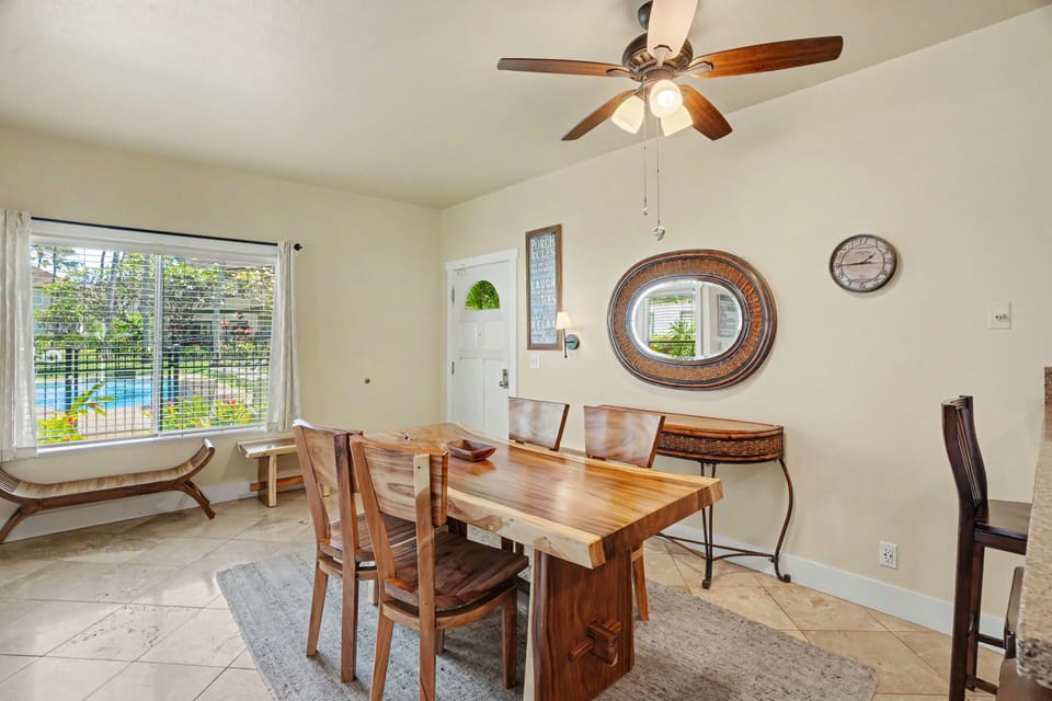 Gather around this warm wooden dining table where meals become memories, with natural light streaming through windows overlooking the pool. Your vacation mornings start here.