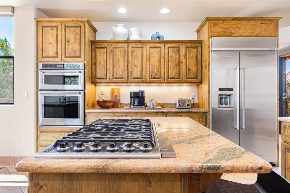 Well-equipped chef's kitchen featuring a luxurious kitchen island, Thor built-in cooktop, and modern appliances.