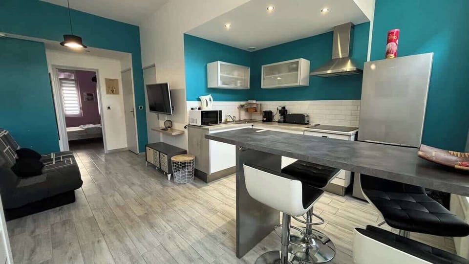 Cuisine ouverte sur le salon, équipée avec four, plaques de cuisson, bouilloire, machine à café, micro-ondes, grille-pain et réfrigérateur avec congélateur.
Coin repas pour quatre personnes.