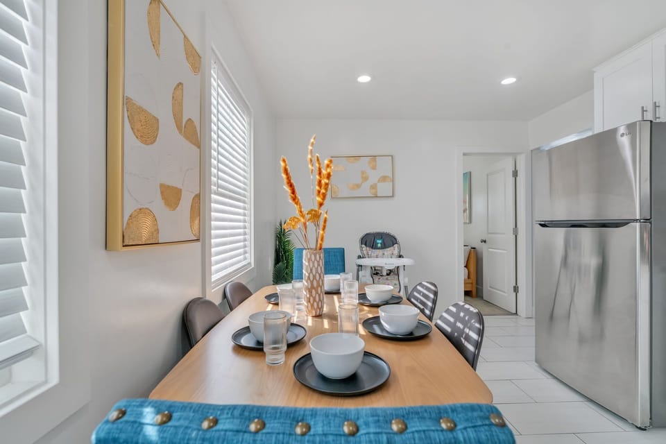 A modern, family dining with a sleek table, blue/gray chairs, and a highchair.