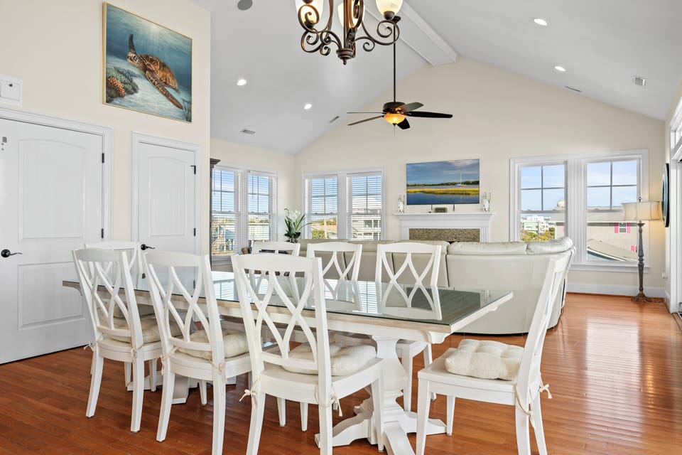 Gather around your elegant dining table where coastal artwork and cathedral ceilings create the perfect setting for memorable meals together.