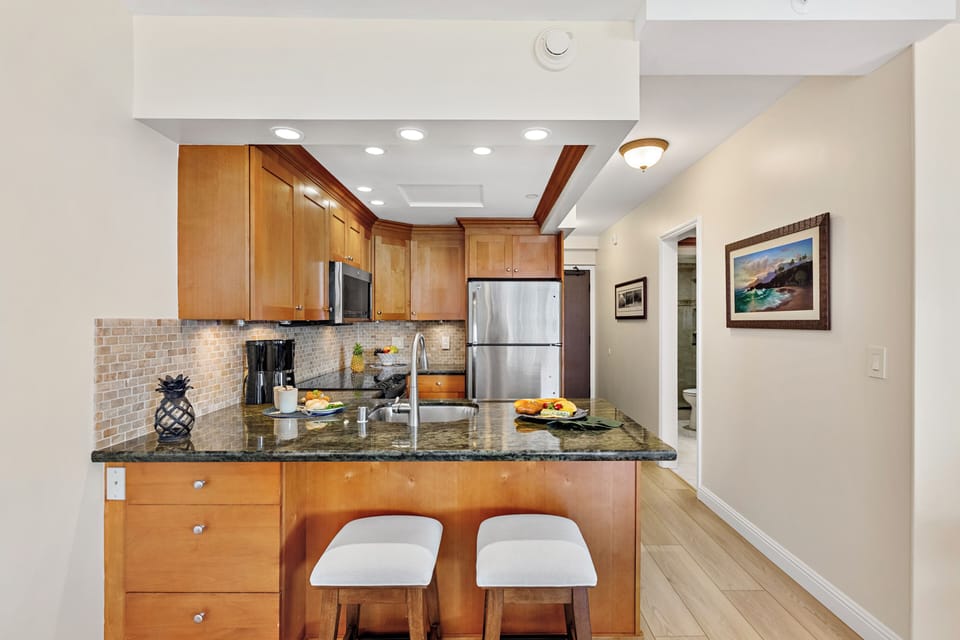 Your fully equipped kitchen awaits with granite counters, stainless appliances, and cozy breakfast bar seating for morning coffee.