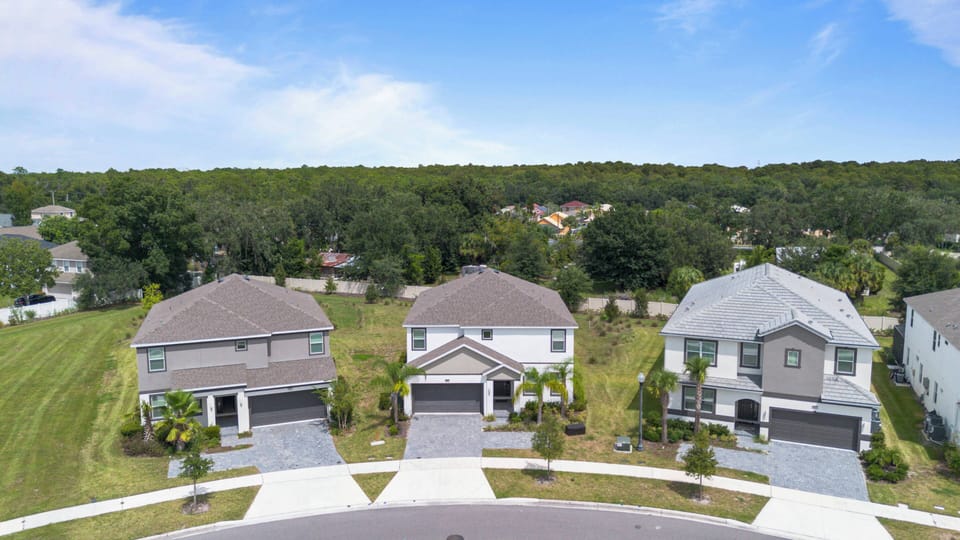 Step outside to admire the beautifully landscaped exteriors of modern vacation homes, framed by lush greenery and a bright blue sky. Each residence showcases tasteful architecture, inviting you to explore the comforts within.