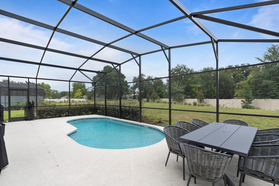 Step outside to unwind by the private pool, beautifully enclosed for comfort and protection. Enjoy outdoor meals at the inviting dark wicker dining set, perfect for a tranquil al fresco experience.