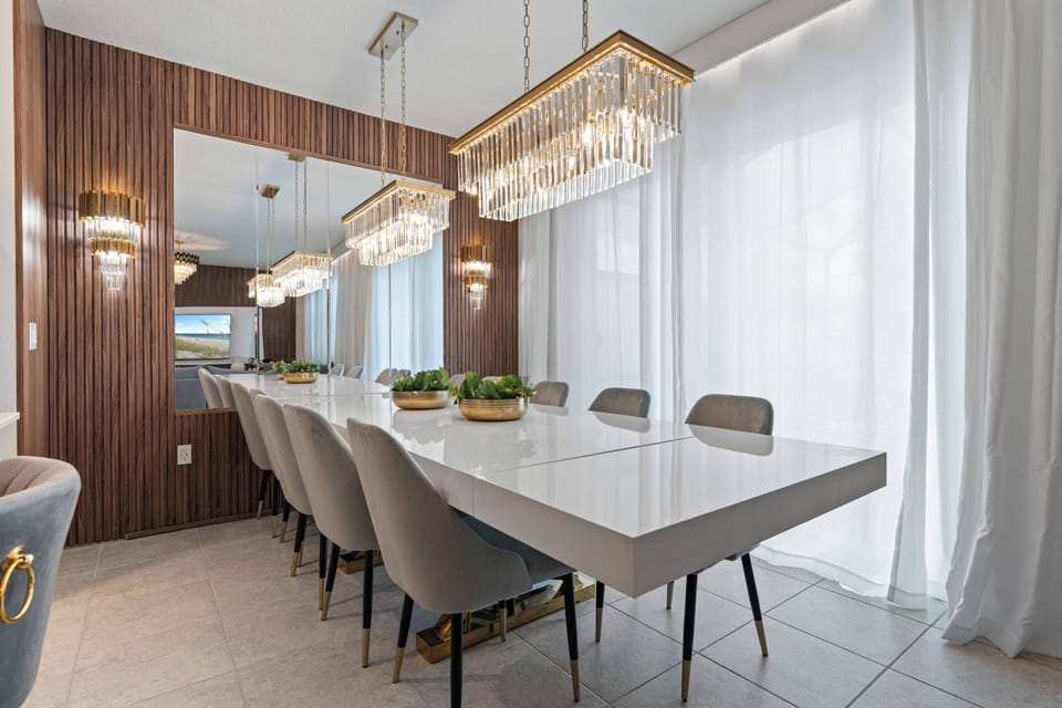 Enjoy a sleek dining area featuring a modern white table with plush gray chairs, elegant lighting for a warm ambiance, and large windows that fill the space with natural light to enhance your dining experience.
