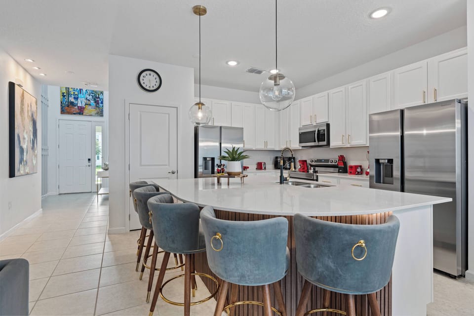 Enjoy a stylish kitchen featuring sleek white cabinetry, a spacious island with comfortable bar stools, modern appliances, and a bright layout—ideal for relaxing meals and casual breakfasts with loved ones.