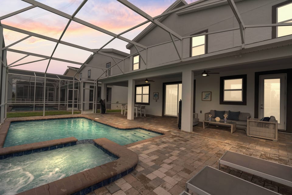 Step into a delightful outdoor oasis featuring a sparkling pool framed by elegant pavers and a cozy seating area. The soft glow from the interior windows invites you to unwind as the colors of dusk create a magical atmosphere.