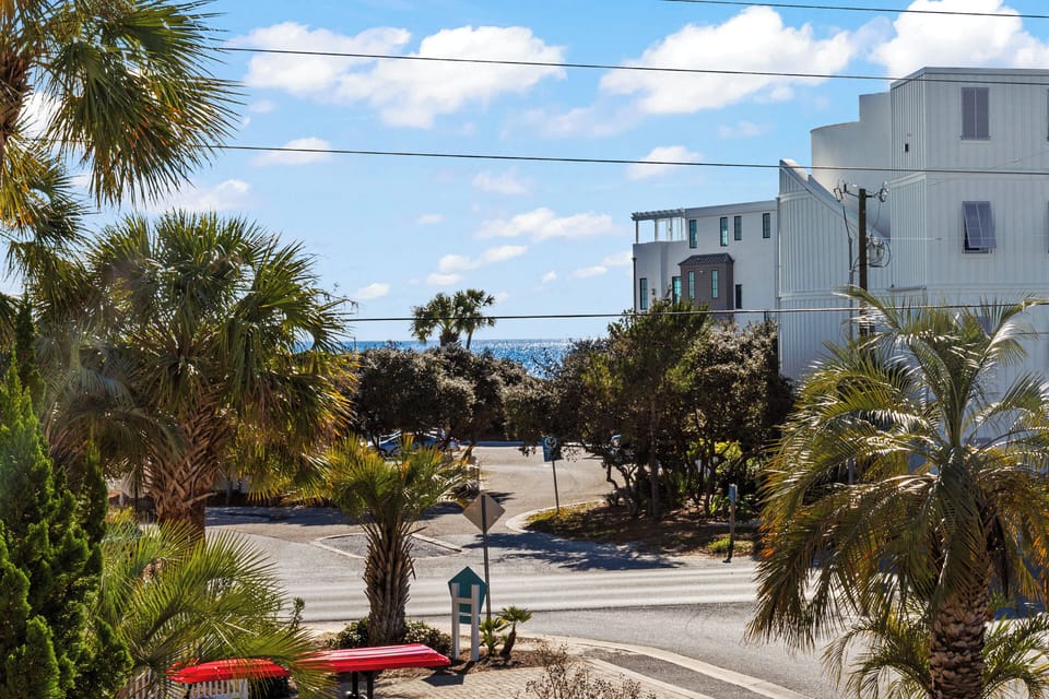 A tranquil coastal neighborhood with tropical palms and ocean glimpses beyond modern buildings—perfect vacation setting.
