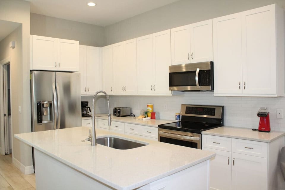 White granite island with faucet and stainless steel appliances.