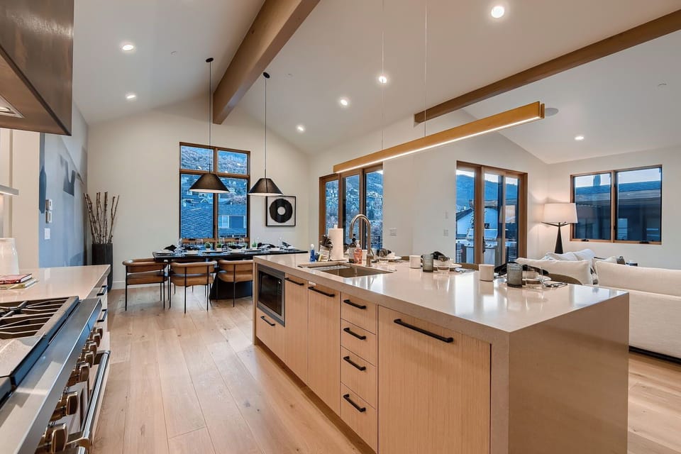 Enjoy gathering in the open-concept living area with a vaulted wood ceiling, functional kitchen island seating, and views of the dining area.