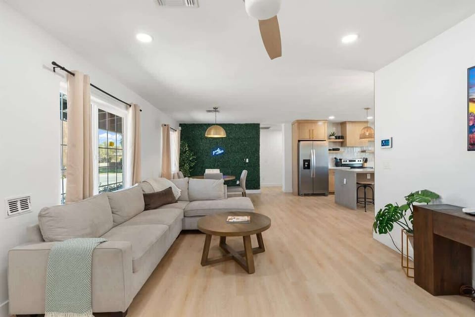 Kick off your shoes in the bright open living area—plush sectional, round coffee table, and sliding doors that pull in daylight, with the kitchen just steps away for snacks.