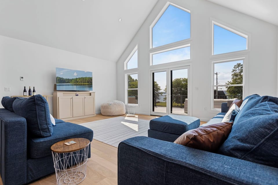 Floor-to-ceiling windows flood the living room with natural light, creating a cozy spot to lounge, sip wine, and enjoy glimpses of the lake.