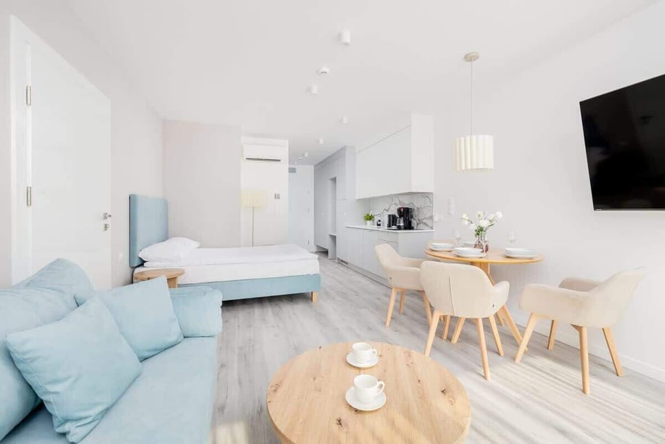 A bright living space featuring a soft blue sofa and wooden furniture. Large windows bring in plenty of daylight.