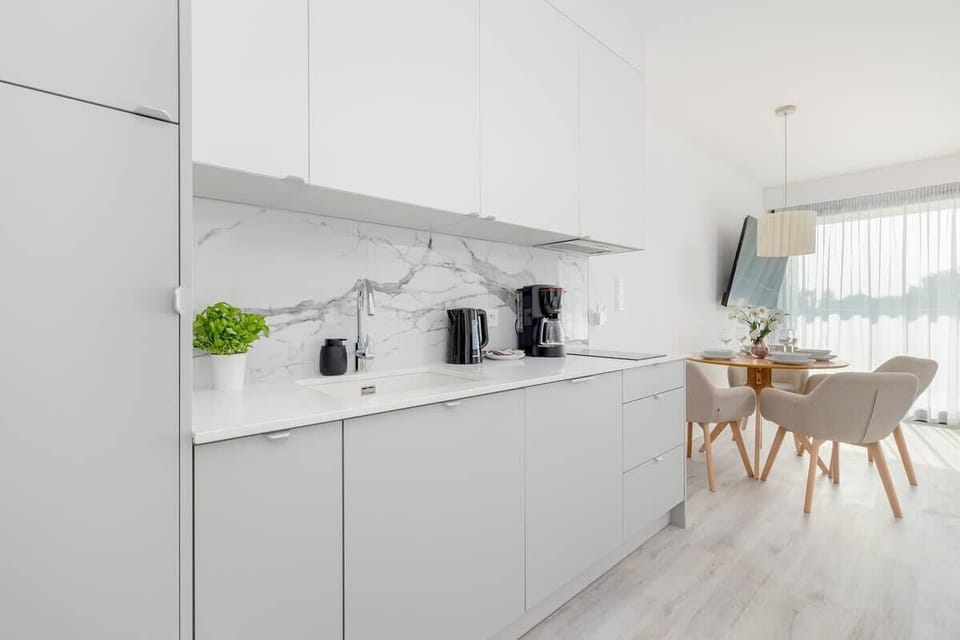 A minimalist kitchenette with modern appliances. Includes a kettle, toaster, and coffee maker.