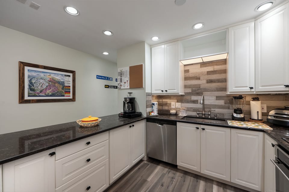 Your fully equipped kitchen features sleek granite counters, stainless appliances, and warm wood backsplash - perfect for cooking memorable vacation meals.