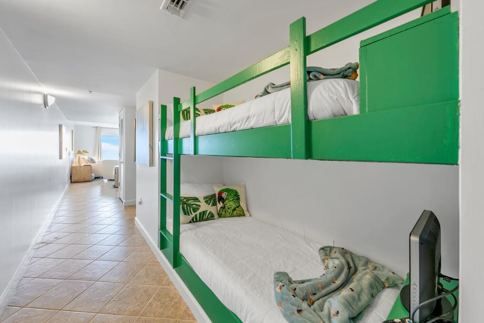 Cozy built-in hallway bunk beds with vibrant green frames create your perfect shared sleeping space, complete with tropical-themed pillows and personal storage.