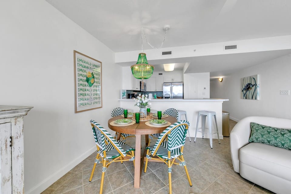 Gather around your stylish dining table with coastal-chic chairs, where emerald accents and modern lighting create the perfect spot for memorable meals.