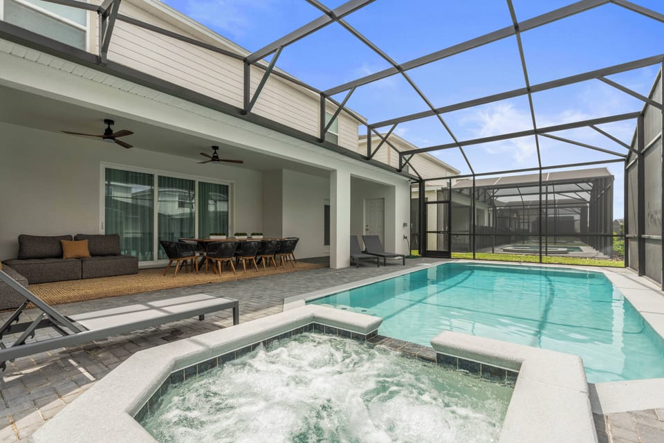 Step into a sunlit oasis where a sparkling pool and bubbling spa invite you to unwind. The modern seating area, paired with a stylish dining set, creates an ideal setting for entertaining or relaxing under the open sky.