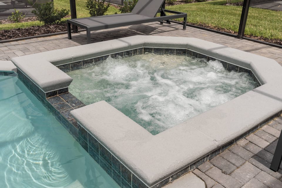 Relax in the luxurious hot tub, surrounded by sleek stone edges and a sparkling pool, perfect for unwinding after a day of exploration. The tranquil setting invites you to soak up the sun on the comfortable lounge chairs nearby.