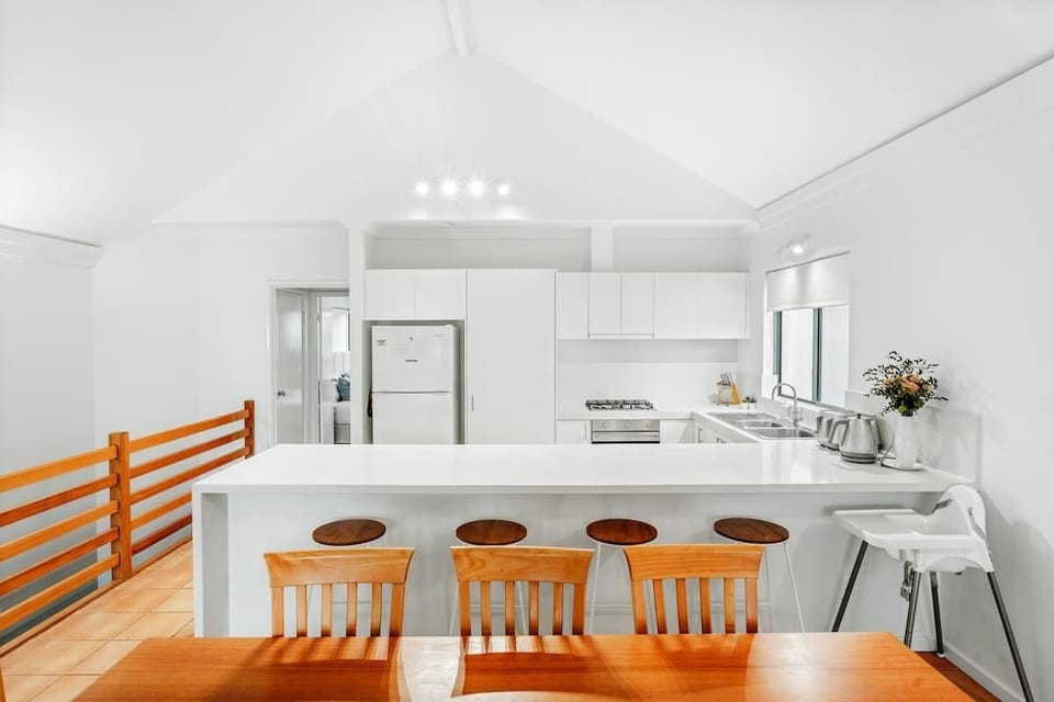 Bright and modern kitchen with a spacious island, gas stove, and fully equipped amenities. Enjoy meals at the breakfast bar or dining table—perfect for family stays.