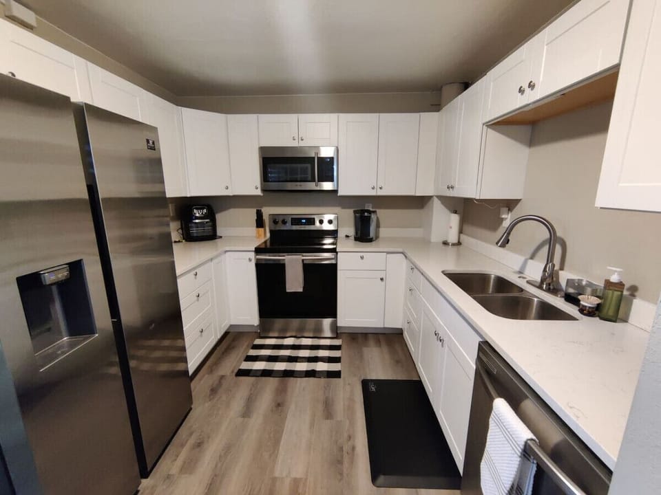 Quiet full kitchen equipped with electric stove, microwave oven, large side by side refrigerator, and dishwasher.