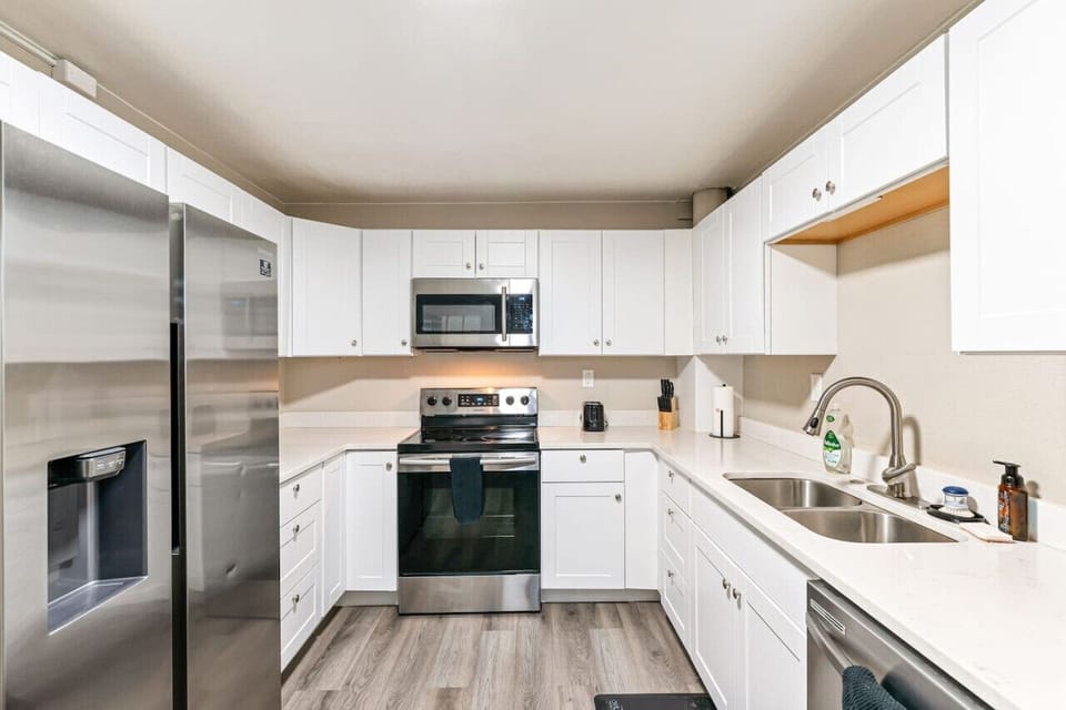 Quiet full kitchen equipped with electric stove, microwave oven, large side by side refrigerator, and dishwasher.