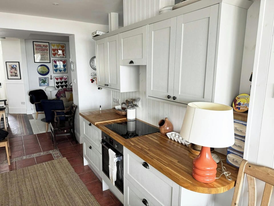 Kitchen with built-in electric oven and hob leading into living area