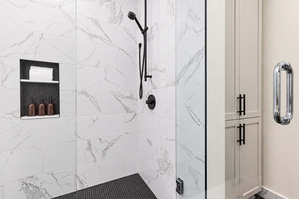 The primary bathroom offers sleek finishes, a soaking tub with Smart TV, walk-in shower, and plush towels. Spacious and private, it adds a luxurious touch to your suite—perfect for unwinding after a day in Downtown New Orleans.