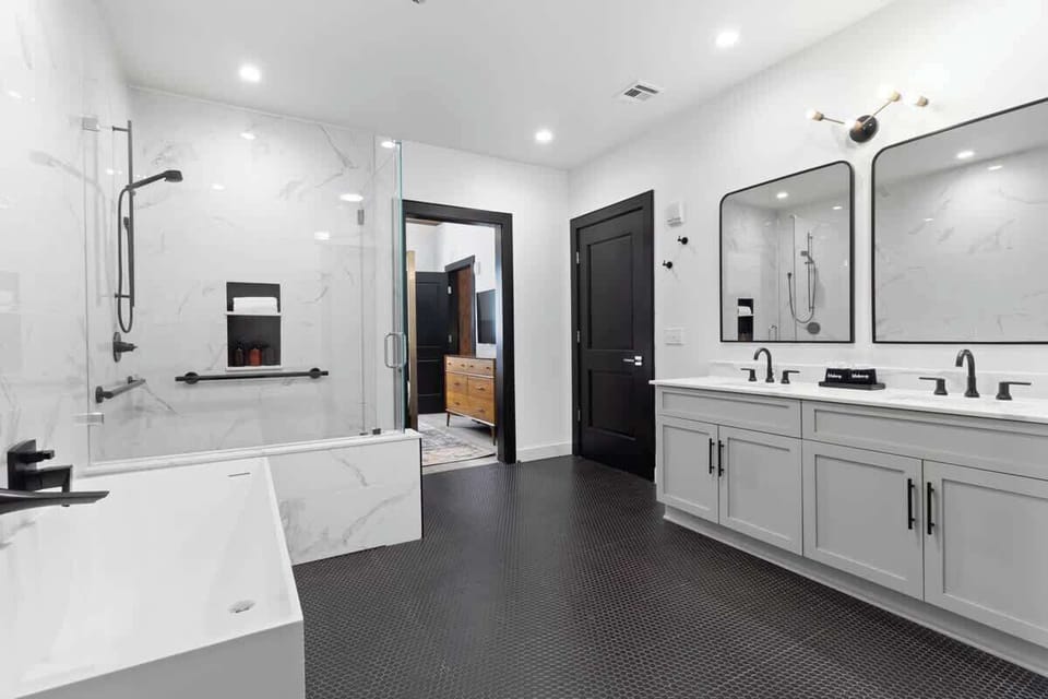 The primary bathroom offers sleek finishes, a soaking tub with Smart TV, walk-in shower, and plush towels. Spacious and private, it adds a luxurious touch to your suite—perfect for unwinding after a day in Downtown New Orleans.