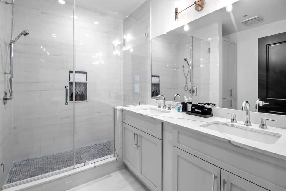 The primary bathroom offers sleek finishes, a soaking tub with Smart TV, walk-in shower, and plush towels. Spacious and private, it adds a luxurious touch to your suite—perfect for unwinding after a day in Downtown New Orleans.