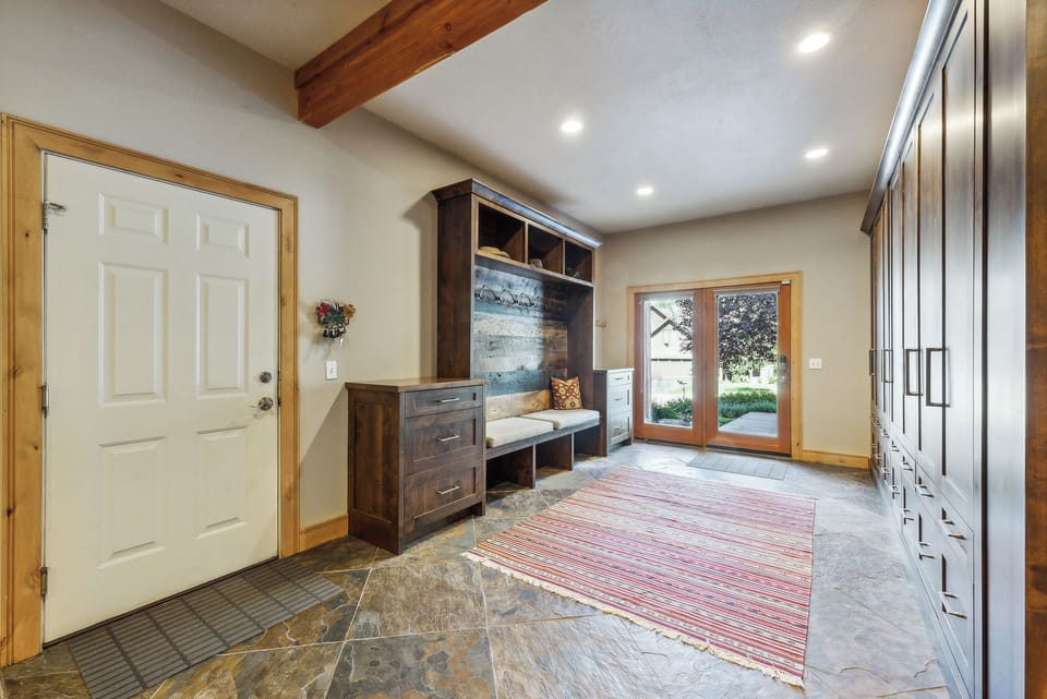 - Mudroom entry with custom wood cabinetry and storage bench  
- Convenient hooks, drawers, and seating for outdoor gear  
- Direct access to the yard and garden pathways