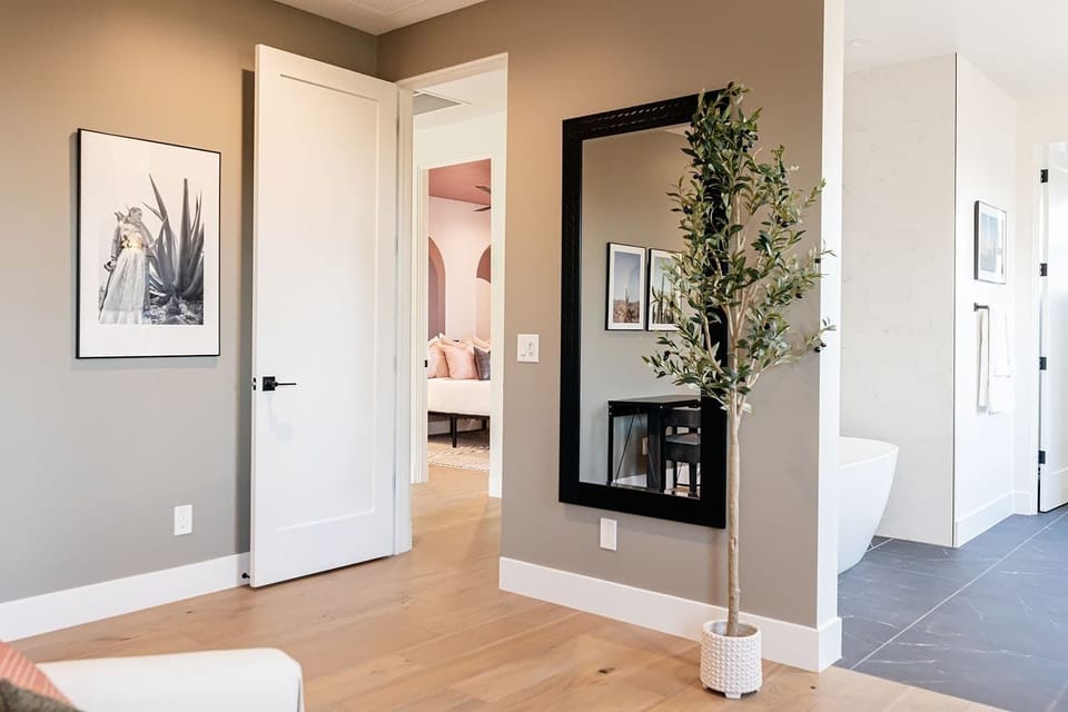 A full-sized mirror beside the door, and a desk with a plush chair on the other side