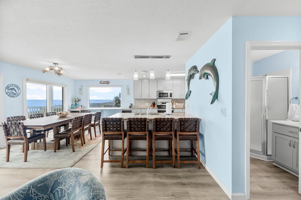 Your spacious kitchen flows seamlessly into the dining area, where ocean views stretch endlessly beyond floor-to-ceiling windows.