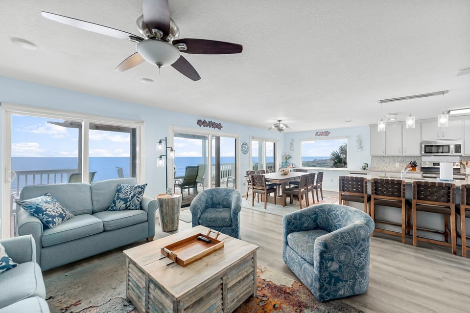 Relax in your coastal haven with stunning ocean views through floor-to-ceiling windows, where gentle ceiling fans create the perfect breeze.