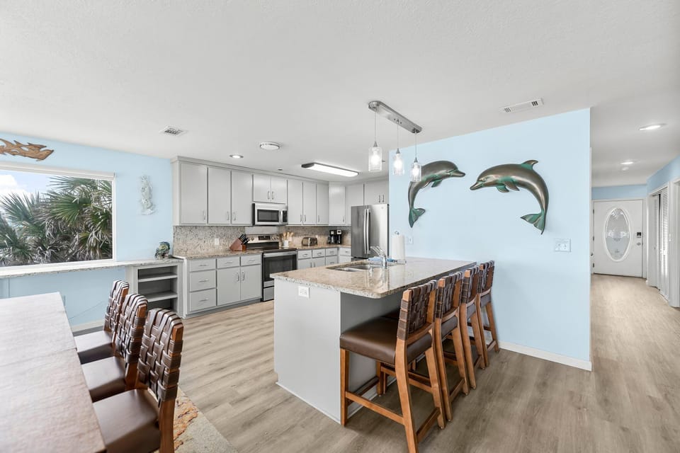 Your coastal-themed kitchen welcomes you with dolphin wall art and modern amenities, perfect for preparing meals together.