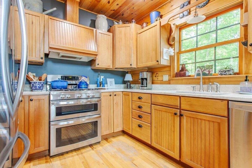 Well-equipped kitchen at Hazy View Cabin showcasing stainless appliances, wood details, and peaceful views of the surrounding trees.