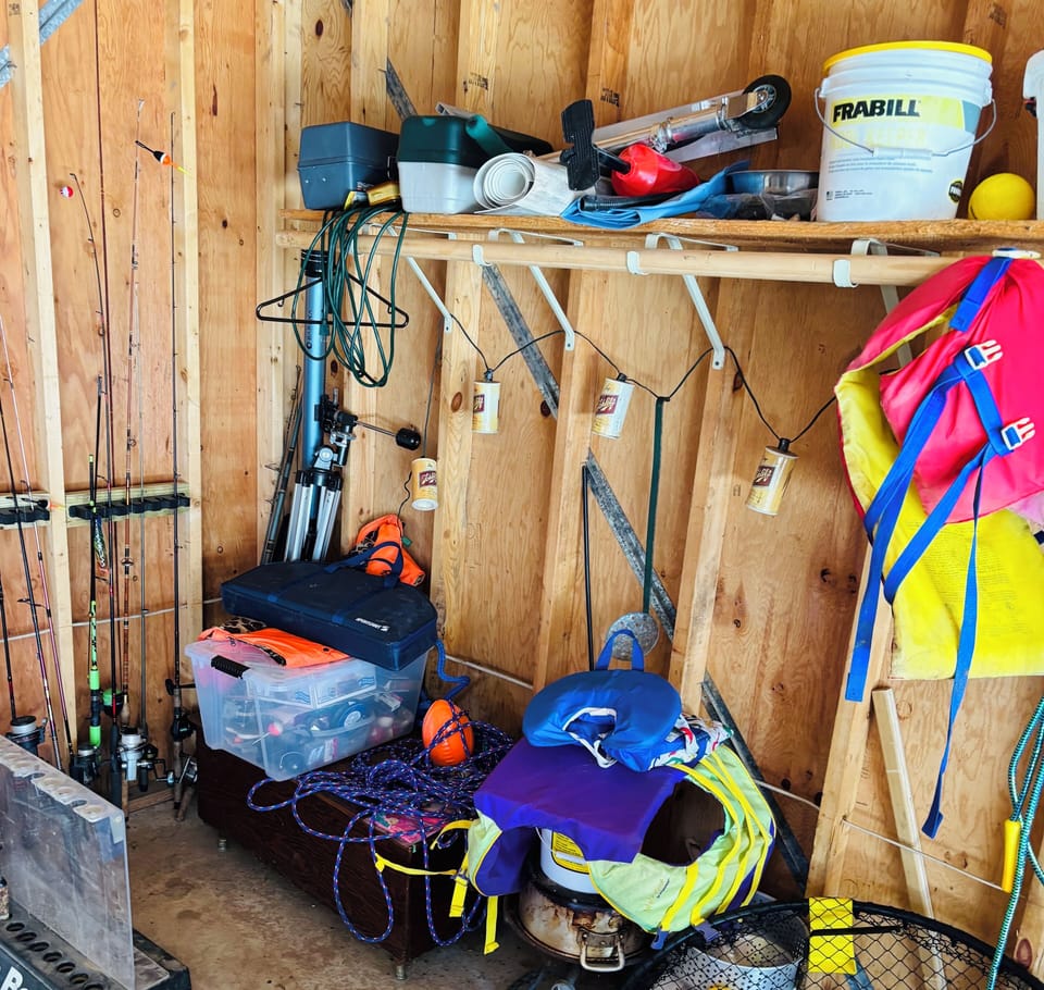 Extras in garage including fishing gear, minow buckets, and life jackets