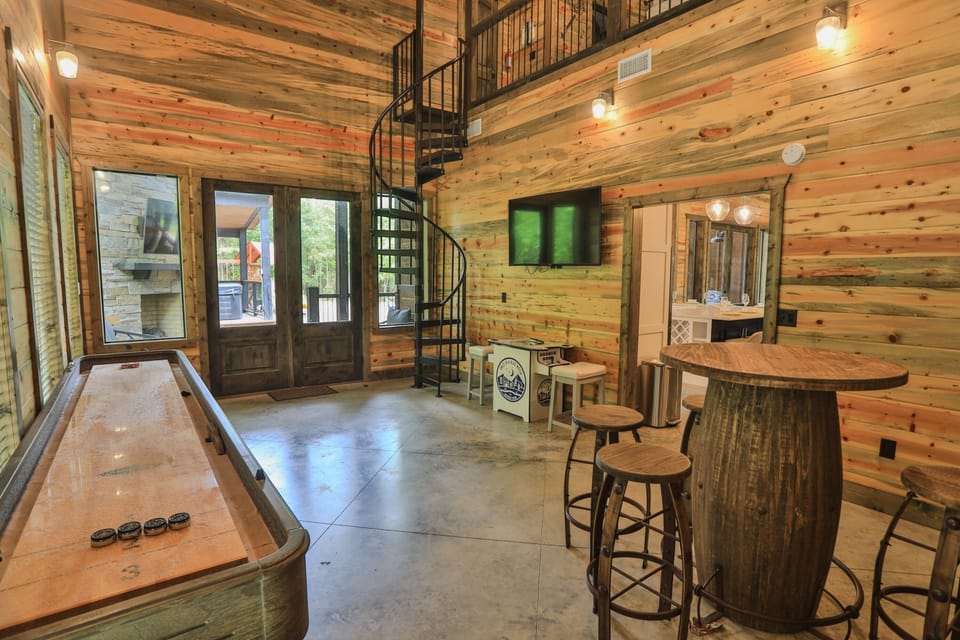 Fun awaits indoors with shuffleboard, an arcade machine, a big-screen TV for entertainment and fun spiral stairs to 2nd floor! | Once in a Blue Moon, Rose Circle, Broken Bow | Voyax Luxury Vacation Rentals