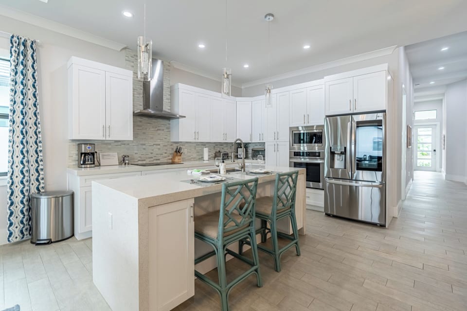 Get ready to whip up delicious meals in this fully-stocked chef’s kitchen! It features bar seating and brand new appliances—perfect for sharing great food and fun times! | Seaside Sanctuary, Naples, Florida | Voyax Luxury Vacation Rentals