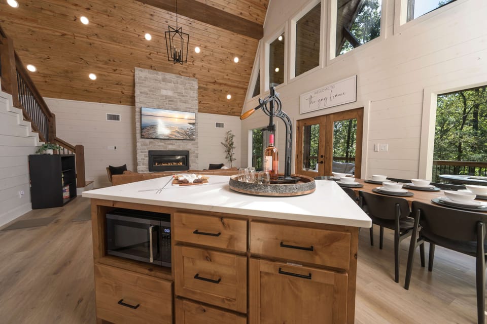Kitchen island with wine opener and luxury living room with forest view.