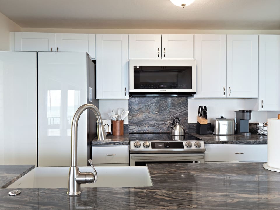 Our kitchen features new glass appliances, granite countertops, and ample space
