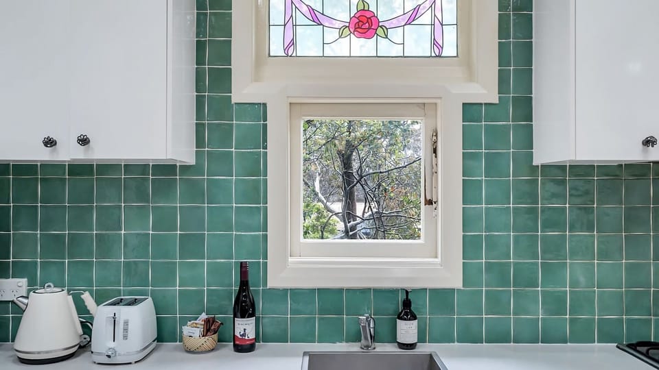 Green tiles, a splash of wine, and a stained-glass rose. Doing the dishes never looked so romantic. 