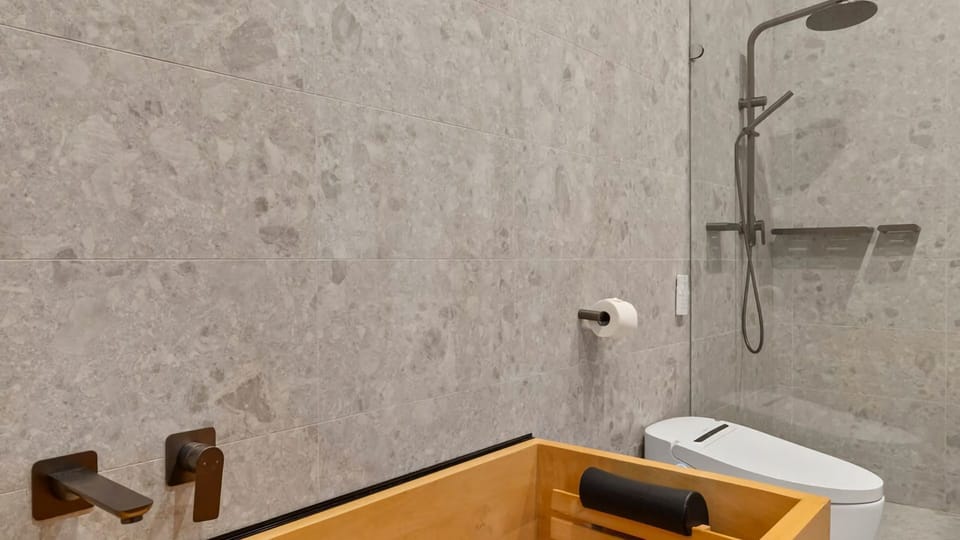 Calm bathing space featuring a Japanese wooden tub and walk-in shower.
