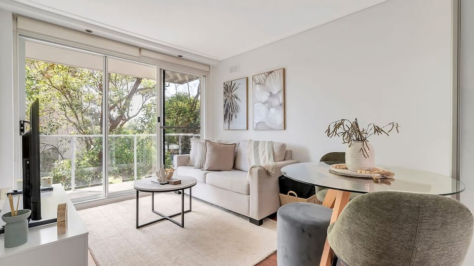 our tranquil city sanctuary. This chic, open-plan space perfectly balances modern comfort with warm details, from the sleek glass dining table to a cozy neutral lounge setup.