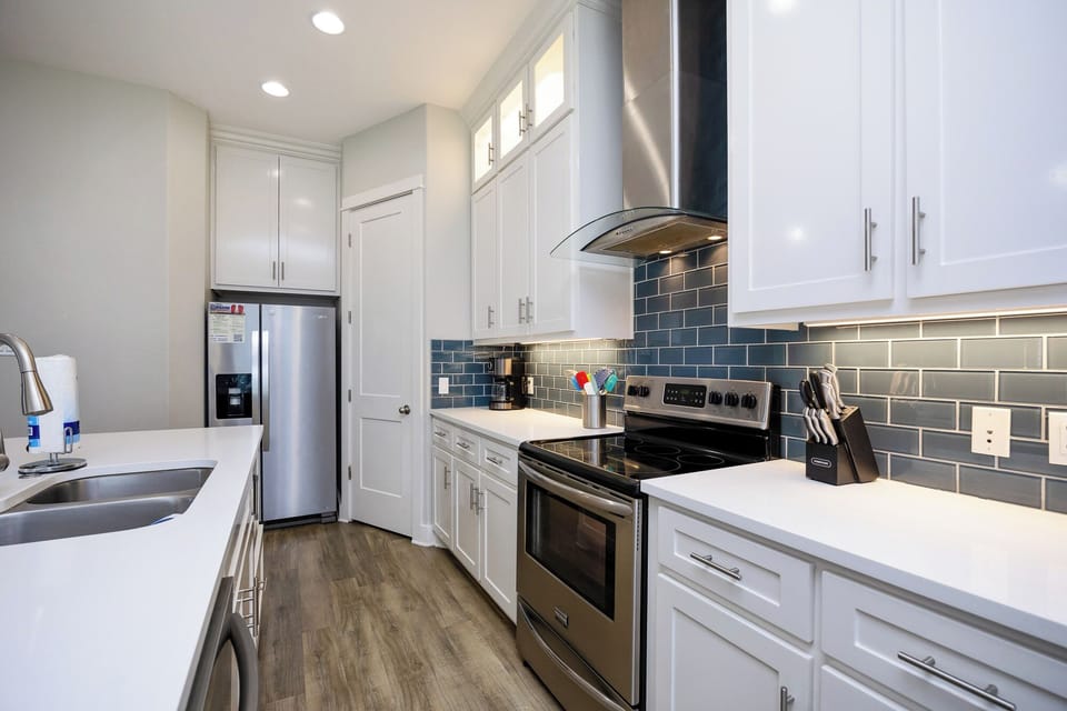Your sleek galley kitchen features pristine white cabinets, stainless steel appliances, and elegant subway tile backsplash for inspired home cooking.